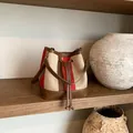 Vintage bucket bag with earth-tone stripes and drawstring closure on a wooden shelf - Khaki