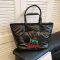Black quilted tote bag with Merry Christmas embroidery and leather handles on sofa - Black