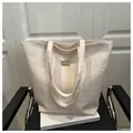 Dettaglio macro della borsa tote bianco crema effetto coccodrillo con logo dorato - Bianco
