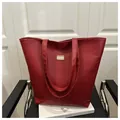 Dettaglio borsa tote rosso scuro con trama a coccodrillo e logo dorato su sedia moderna - Rosso
