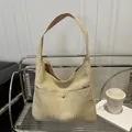 Beigefarbene gewebte Umhängetasche mit Metallschnalle auf modernem Stuhl für den Sommer - Khaki