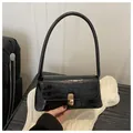 Elegante schwarze Schultertasche mit Krokodilprägung und goldenem Metallverschluss - Schwarz
