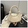 Detail of a half-moon off-white faux leather handbag with spherical handle accents - White
