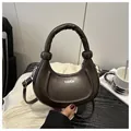 Detail of dark brown crescent bag with FASHION text and plush handle on a cozy background - Coffee