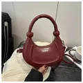 Detail of burgundy crescent handbag showing the twisted handle knots and silver logo - Red
