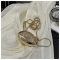 Dettaglio clutch a conchiglia dorata con texture in metallo martellato e catena snake - Oro