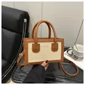 Close-up of contrast color square bag with Anniv 1986 text and gold hardware - Brown Splicing Canvas (Anniv 1986) / Dark Brown