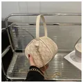 Dettaglio della mini borsa cilindrica beige con monogramma M e tracolla a catena d'oro - Bianco