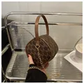 Dettaglio di una mini borsa rotonda monogramma con manico in pelle e catena d'oro - caffè