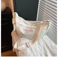 Dettaglio di una borsa a mezzaluna in nylon bianco con scritte rosa e tracolla larga - Bianco