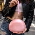 Chic pink pearlescent acrylic clutch bag with wrist strap shown in urban setting - Pink