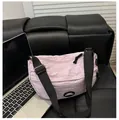 Dettaglio borsa a mezzaluna in nylon lilla con patch Lucky Fashion su sfondo in pelle nera - Viola