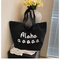 Detail of black canvas tote bag showing white script lettering and a large storage compartment - Black