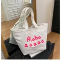 Detail shot of large white canvas tote bag with pink Alaha print and artistic letters - White