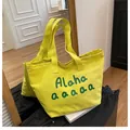 Detail of the bright yellow canvas tote bag showing the texture and artistic lettering - Yellow