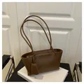 Detail view of a vintage dark brown leather tote bag with a rectangular tag and slim straps - Coffee