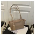 Detail of a minimalist beige tote bag with slim straps on a leather chair and books - Khaki