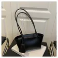 Detail view of black minimalist tote bag with slim shoulder strap on a white background - Black