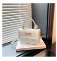 Detail of white glossy mini bag with wavy flap, gold bow accent and knot handle detail - White