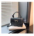 Detail of black mini crossbody bag featuring a wavy flap and golden bow ornament - Black