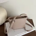 Minimalist beige matte leather bucket bag with adjustable strap and embossed brand logo - Khaki
