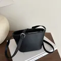 Chic black faux leather bucket bag with adjustable strap and embossed logo detail - Black