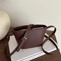 Dark brown leather bucket bag with adjustable strap and metallic zipper closure - Brown