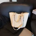 Borsa tote in paglia color crema intrecciata con ampi manici in tessuto e lettere nere - Bianco
