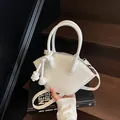 Chic white shell-shaped handbag with decorative knot handle and gold-tone zipper - White
