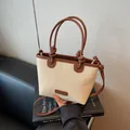 Beigefarbene Stroh-Beuteltasche mit dunkelbraunem Lederbesatz und Knotengriff-Detail - Dunkelbraun