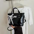 Sac seau en cuir verni noir brillant avec nœud en dentelle et perles sur fond de robe blanche - Avec Pendentif / Noir
