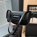 Sleek black baguette underarm bag with large square buckle and matte leather finish - Black
