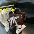 Brown patent leather bucket bag with lace bow and pearl charm for women in 2025 style - Coffee
