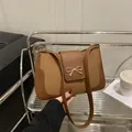 Brown woven saddle bag with leather trim and golden bow metal buckle on glass shelf - Dark Brown