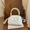 Borsa a tracolla in ecopelle beige con finiture dorate su una sedia in legno - Bianco