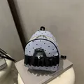 Mini mochila de rayas con corazones y lazo negro sobre un libro gris decorativo - Azul