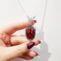 Vintage versilberte Halskette mit ovalem rotem Steinanhänger und filigranen Details - Taubenblutrot