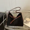 Black matte tote bag with brown leather straps and metal buckles in a lifestyle scene - Black