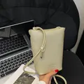 Champagne gold mini crossbody bag with lychee texture and knot detail on black velvet - Gold
