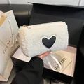 White faux fur cylindrical handbag featuring a black heart patch and gold zipper - White