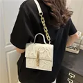Elegant white embossed faux leather handbag with gold chain strap and top handle design - White