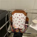 White cherry print bucket bag with brown leather trim and colorful woven strap - Dark Brown