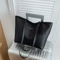 Bolso tote negro minimalista con letras doradas sobre una maleta de metal plateado - Negro