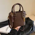 Bolso cubo marrón de cuero granulado con colgante de oso dorado y asa de mano - Marrón