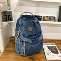Mochila de tela vaquera azul oscuro con tiradores marrones sobre una mesa de madera - Azul oscuro