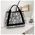 Dettaglio della borsa tote in tela zebrata con manici neri e logo stampato - Zebra Print
