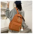 Detailed back view of a caramel student backpack with a soft white plush ball charm - Orange