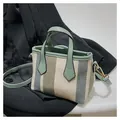 Detalle del bolso de lona tejida multicolor con correa de cuero verde y herrajes dorados - Gris