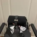 Bolso de hombro negro mate con hebilla metálica en forma de H plateada sobre revista - Negro