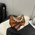Brown mini bow handbag with pearl handle and studded accents in a lifestyle setting - Brown